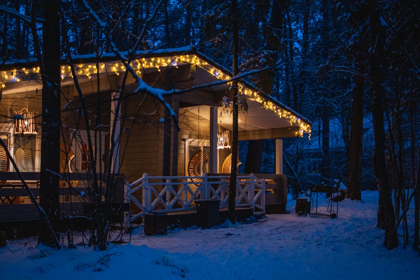 A snow-covered cabin glows with lights in a winter forest.