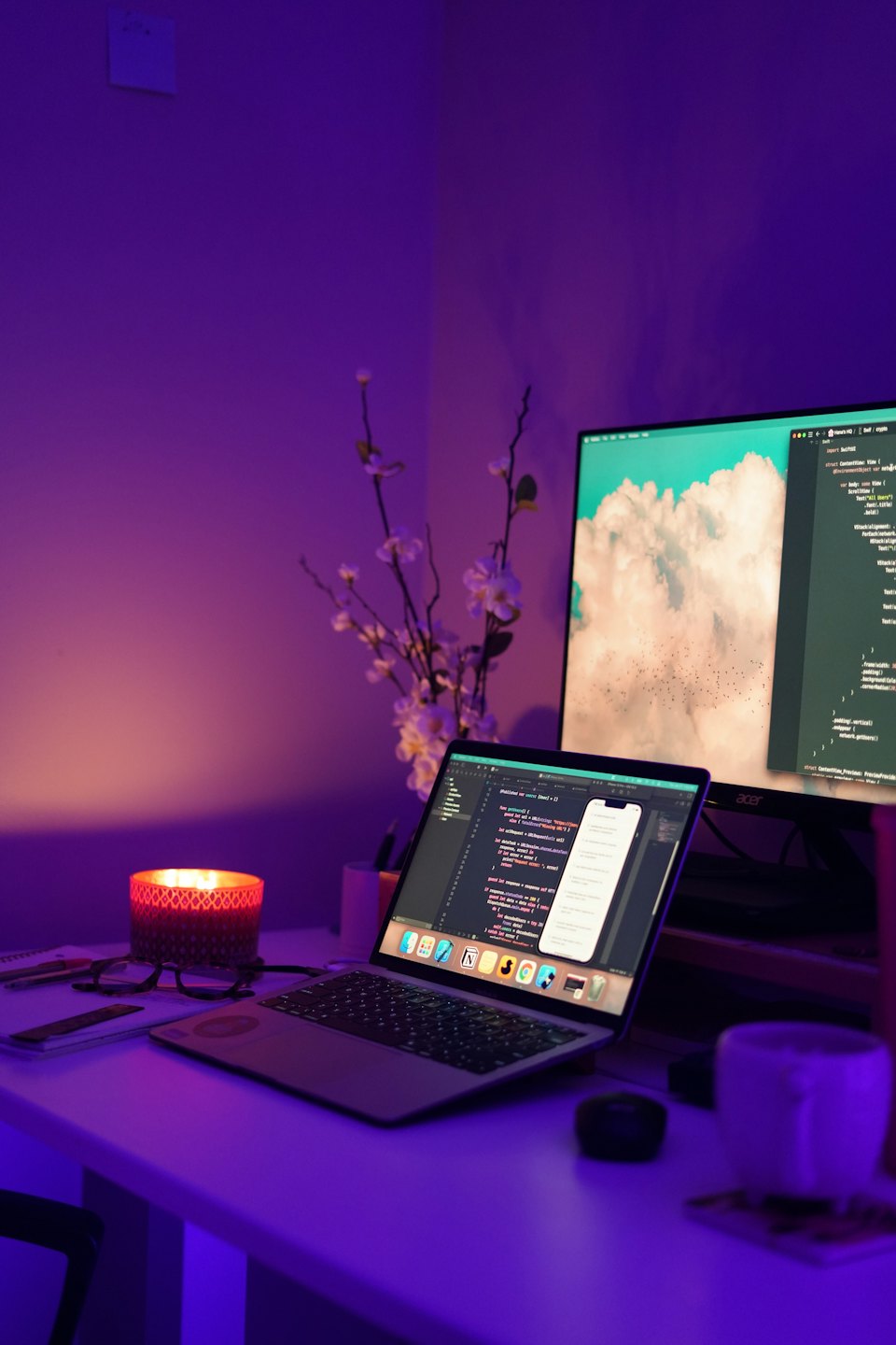 Developer's desk with laptop, monitor, and candle.